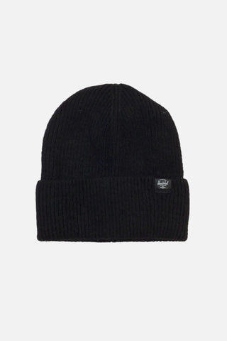 A black ribbed knit beanie hat with a folded cuff, featuring a small white embroidered logo patch on the side, set against a plain off-white background.